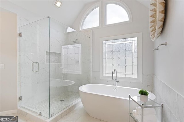 full bathroom with a shower stall, vaulted ceiling, tile walls, and a freestanding bath