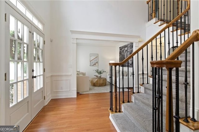 foyer entrance featuring wood finished floors, a decorative wall, french doors, and a wealth of natural light