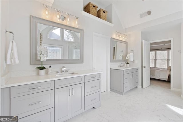 bathroom featuring visible vents, marble finish floor, ensuite bathroom, a sink, and vaulted ceiling