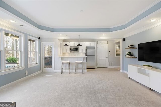 unfurnished living room featuring visible vents, ornamental molding, baseboards, a raised ceiling, and light colored carpet