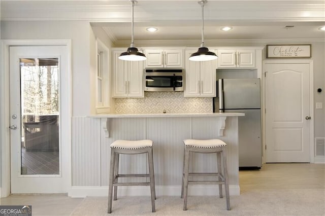 kitchen featuring hanging light fixtures, appliances with stainless steel finishes, and a breakfast bar