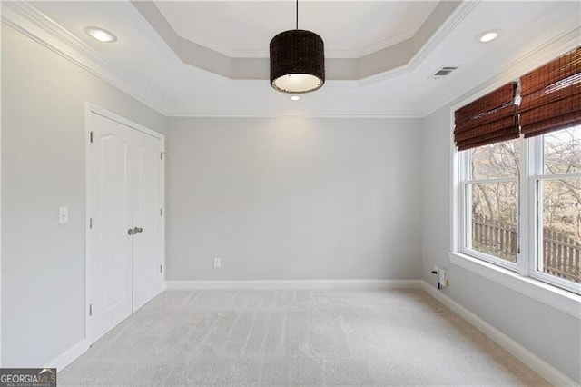 spare room featuring a raised ceiling, crown molding, baseboards, and light carpet