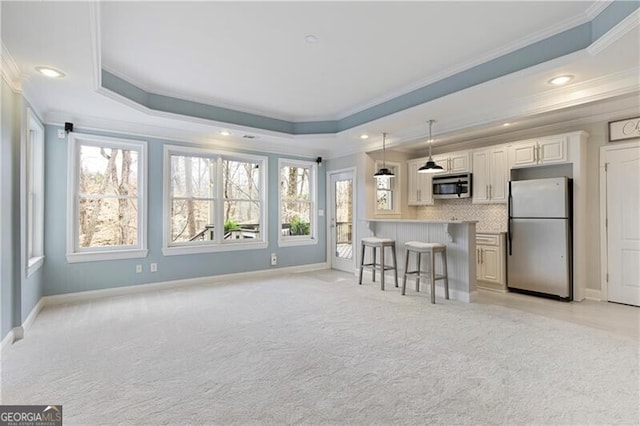 kitchen with plenty of natural light, appliances with stainless steel finishes, a raised ceiling, and a kitchen breakfast bar