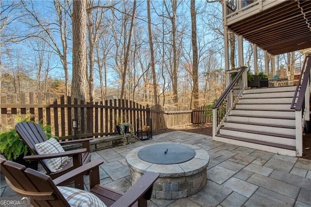 view of patio featuring stairway, an outdoor fire pit, and fence