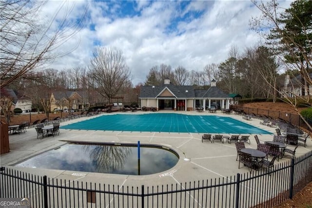 community pool with a patio and fence