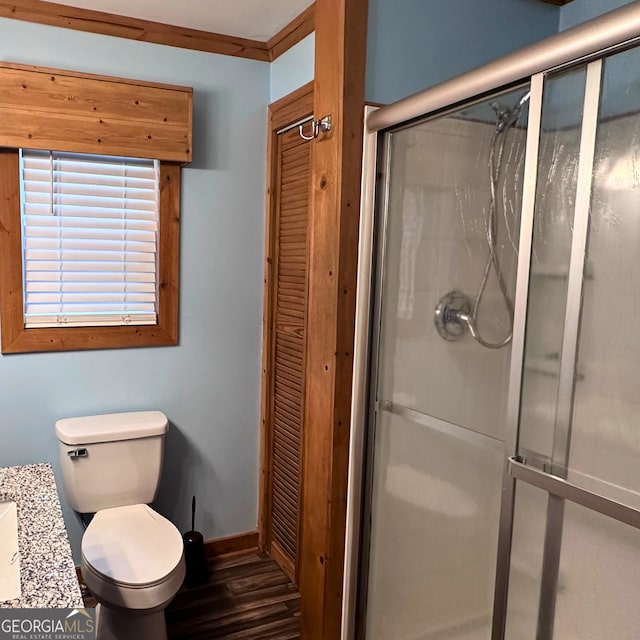 full bathroom with a shower stall, toilet, wood finished floors, and baseboards