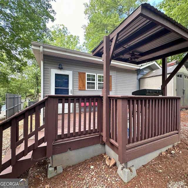 deck featuring ceiling fan, a storage shed, a grill, and an outdoor structure