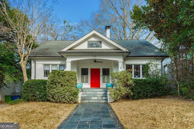 view of front of house featuring a front yard, brick siding, and a shingled roof