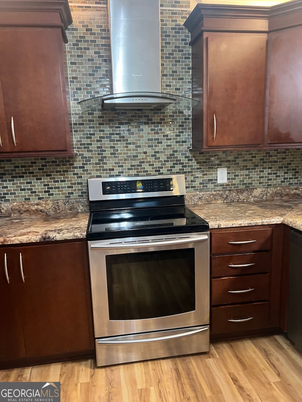 kitchen featuring decorative backsplash, wall chimney range hood, stainless steel electric stove, and light wood-type flooring