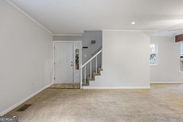 carpeted entryway featuring visible vents, stairway, baseboards, and ornamental molding