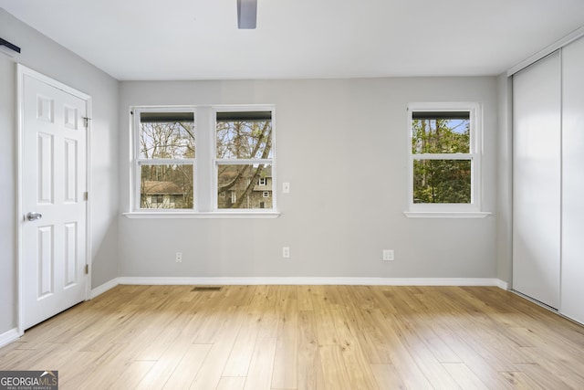 unfurnished bedroom featuring a ceiling fan, visible vents, light wood-style floors, and baseboards