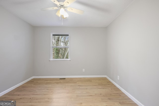 empty room with visible vents, light wood-style floors, baseboards, and ceiling fan