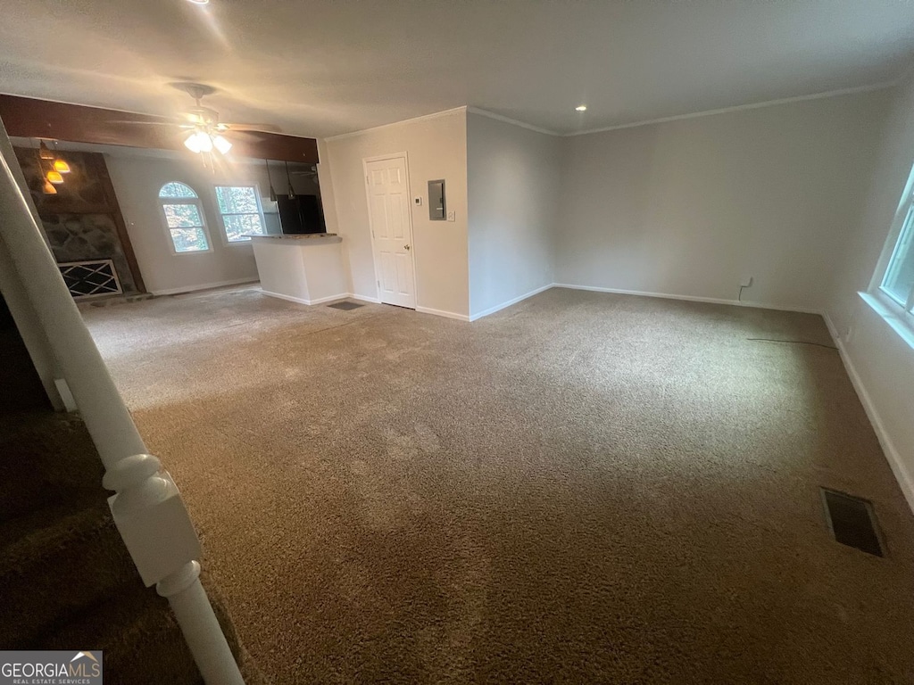 unfurnished living room with visible vents, ornamental molding, ceiling fan, and carpet floors