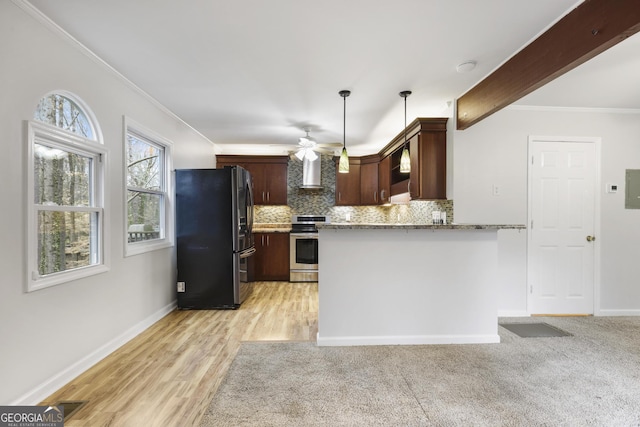 kitchen featuring tasteful backsplash, crown molding, wall chimney range hood, stainless steel range with electric stovetop, and freestanding refrigerator