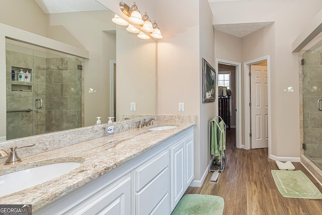 bathroom with a shower stall, wood finished floors, baseboards, and a sink