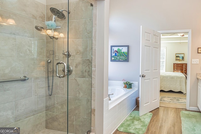 bathroom with ensuite bath, a shower stall, a garden tub, and wood finished floors