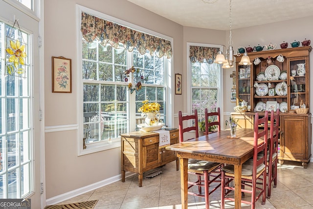 dining area with light tile patterned floors, a notable chandelier, and baseboards