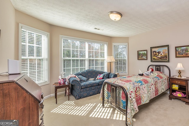 bedroom featuring visible vents, multiple windows, a textured ceiling, and carpet floors