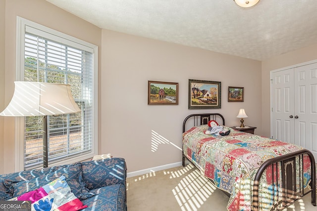 carpeted bedroom featuring a closet, baseboards, and a textured ceiling