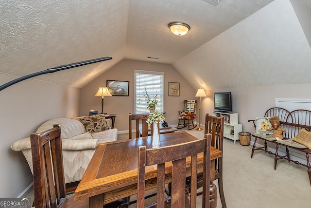 dining area featuring visible vents, a textured ceiling, carpet floors, and vaulted ceiling