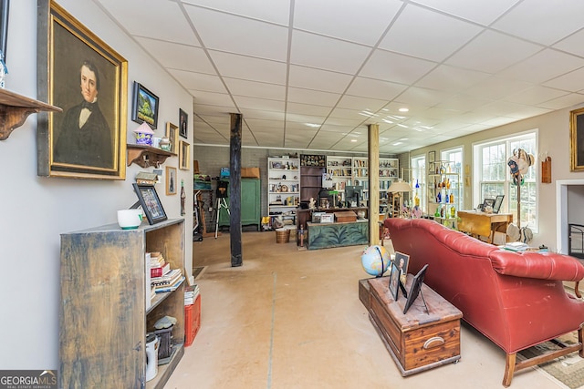 living room with a paneled ceiling and concrete flooring