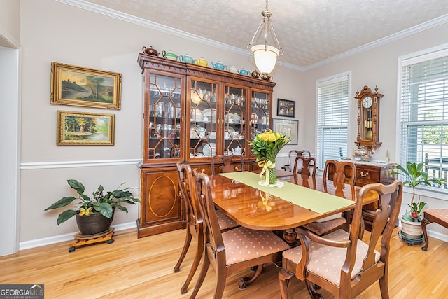 dining area with baseboards, a textured ceiling, ornamental molding, and light wood finished floors