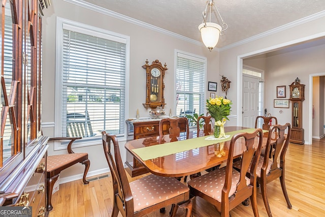 dining area featuring plenty of natural light, a textured ceiling, light wood-style flooring, and ornamental molding