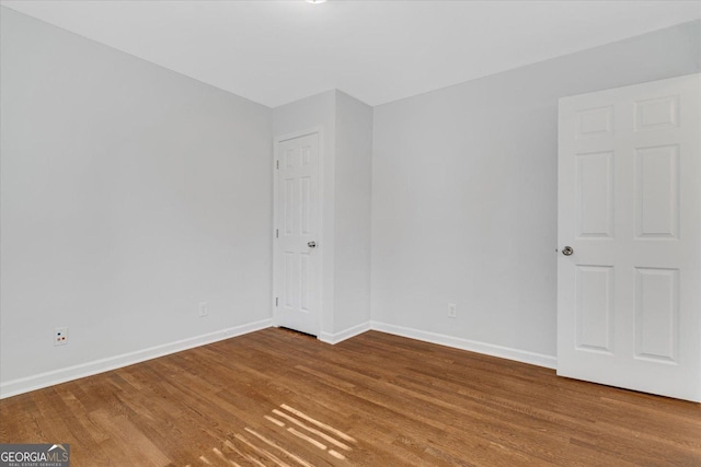 spare room with baseboards and wood finished floors