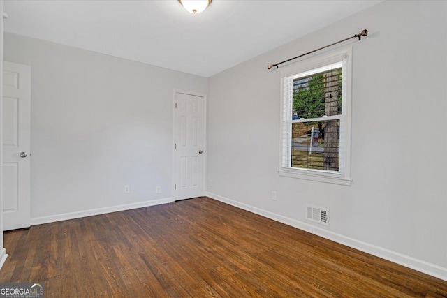 unfurnished room with visible vents, baseboards, and dark wood finished floors