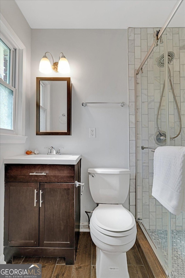 full bath with vanity, a shower stall, toilet, and wood finish floors