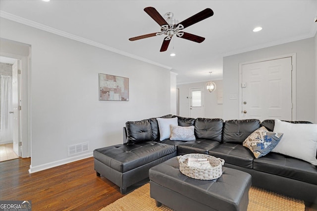 living area with visible vents, crown molding, baseboards, wood finished floors, and a ceiling fan