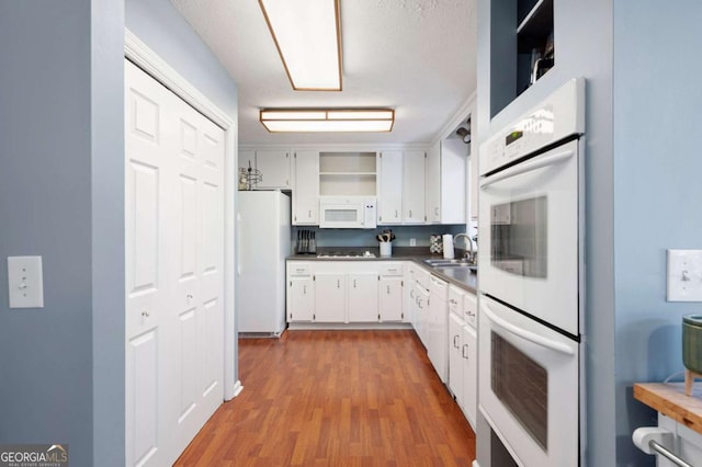 kitchen featuring open shelves, a sink, dark countertops, white appliances, and white cabinets