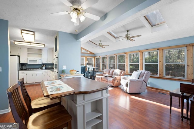 kitchen with white appliances, dark wood finished floors, open shelves, vaulted ceiling with skylight, and white cabinetry