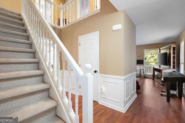 staircase featuring wood finished floors and wainscoting