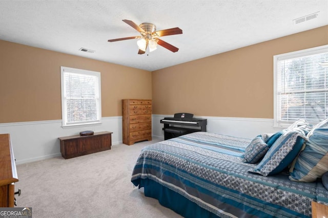 carpeted bedroom featuring visible vents, multiple windows, and a textured ceiling