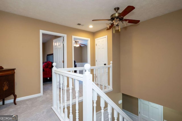 corridor featuring light colored carpet, an upstairs landing, visible vents, and baseboards