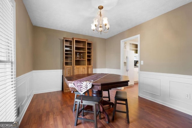 dining area with dark wood finished floors, visible vents, wainscoting, and an inviting chandelier