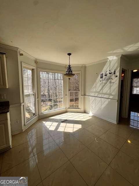 unfurnished dining area featuring tile patterned floors and ornamental molding