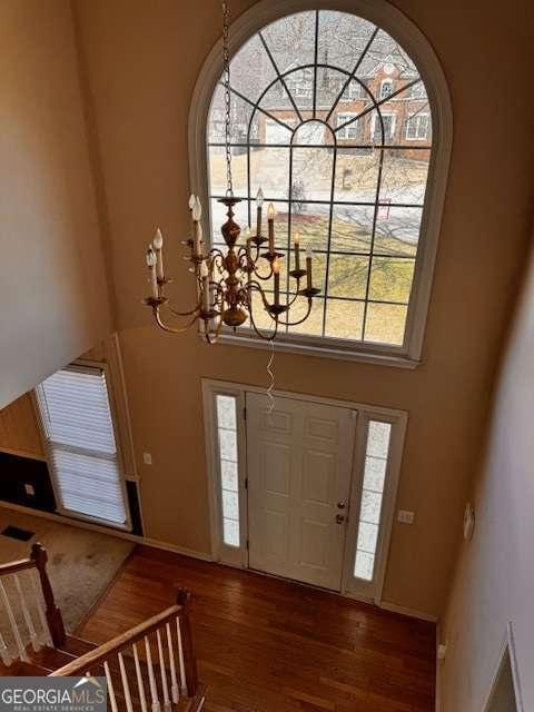 entrance foyer featuring wood finished floors, baseboards, a towering ceiling, and a chandelier