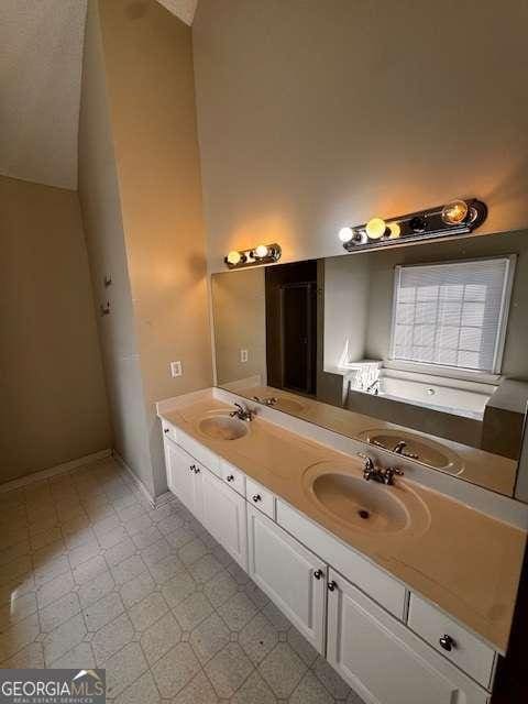 full bath with a sink, double vanity, and tile patterned floors