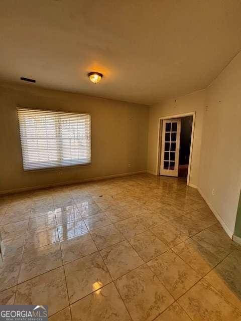 tiled spare room featuring visible vents and baseboards