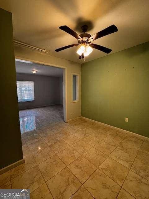 tiled spare room with a ceiling fan and baseboards