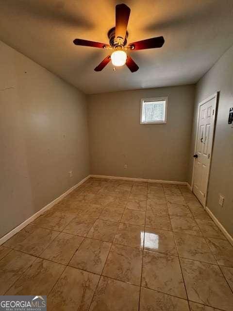 empty room with light tile patterned floors, baseboards, and ceiling fan