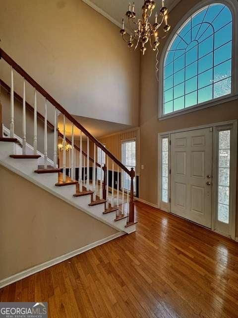 foyer entrance with a notable chandelier, stairs, a high ceiling, and wood finished floors