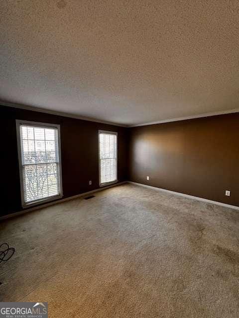 unfurnished room with visible vents, baseboards, a textured ceiling, and carpet flooring