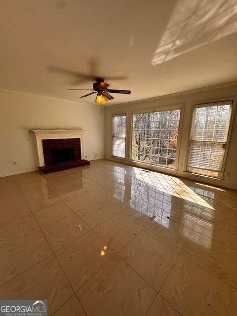 unfurnished living room featuring ceiling fan, baseboards, a fireplace with raised hearth, and crown molding