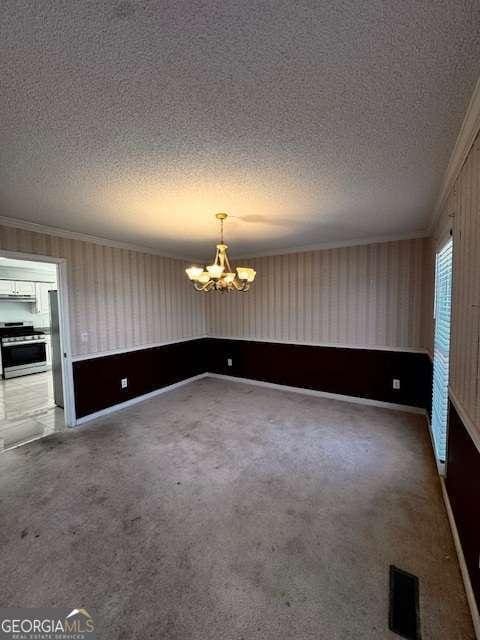 unfurnished room featuring a textured ceiling, crown molding, an inviting chandelier, and carpet floors