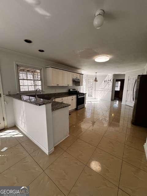 kitchen with plenty of natural light, a peninsula, stainless steel gas range, and freestanding refrigerator