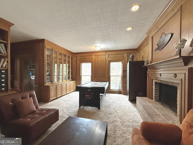 playroom with ornamental molding, a fireplace, a textured ceiling, wood walls, and light colored carpet