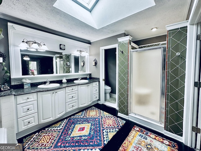 bathroom with ornamental molding, a stall shower, a textured ceiling, a skylight, and a sink